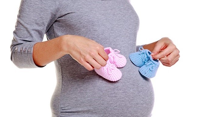 Pregnant woman holding baby booties.